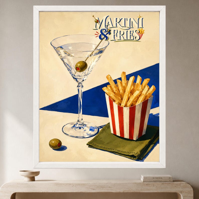 May include: A framed art print featuring a martini glass with an olive, a red and white striped container filled with golden french fries, and a green napkin. The text MARTINI & FRIES is displayed in blue and red script against a cream background.