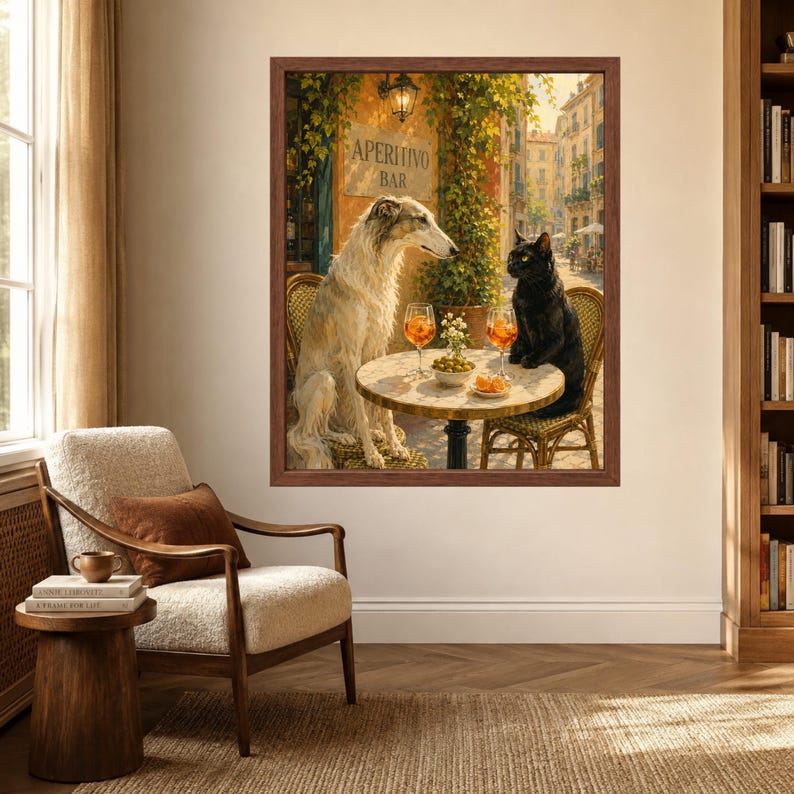 May include: A framed wall art print depicting a white Borzoi dog and a black cat sitting at a small round table outside an Aperitivo Bar. The table holds two orange cocktails and a bowl of olives. The scene is set on a sunny street with greenery.