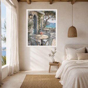 May include: A framed wall art print depicting a Mediterranean outdoor cafe scene with round tables, woven chairs, and potted plants on a stone patio overlooking a blue sea with a sailboat, displayed in a bedroom with a woven pendant light.