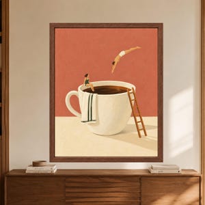May include: A framed wall art print featuring a large white coffee cup filled with dark liquid. A person in a green swimsuit sits on the rim with a white towel, while another person in white shorts dives into the coffee. A wooden ladder leans against the cup.