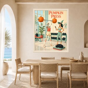 May include: A framed wall art print titled PUMPKIN PRESS featuring a skeleton lifting a barbell with pumpkins as weights, accompanied by a person in a witch hat and green workout clothes, with a black cat resting on a mat in a gym setting.