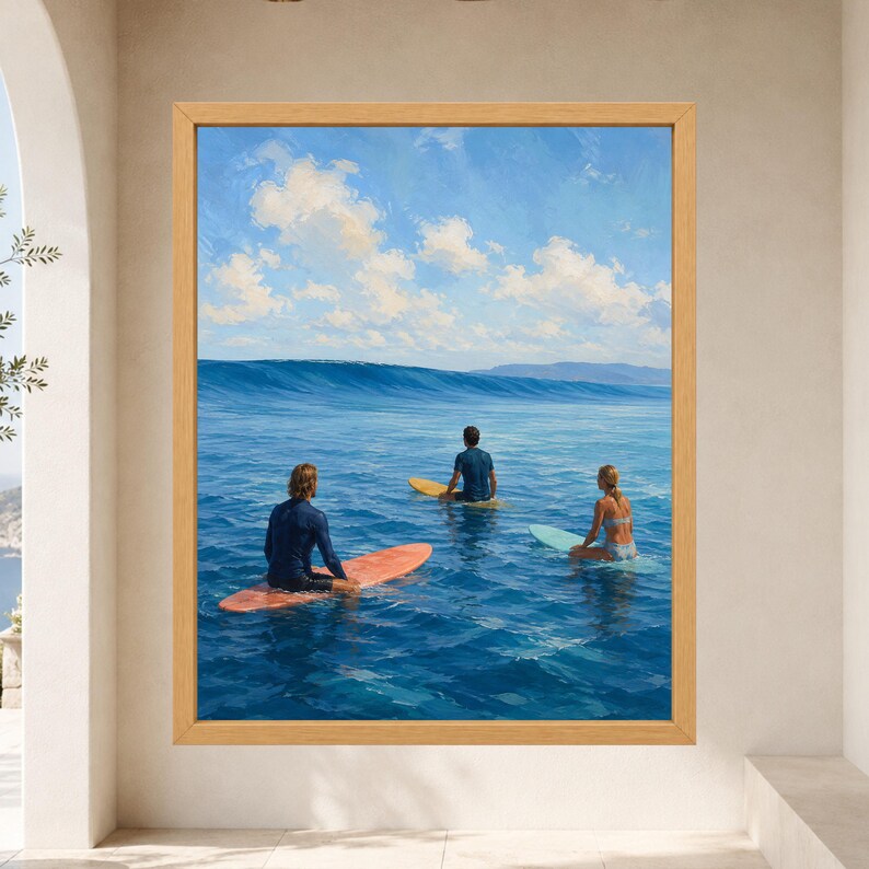 May include: A framed wall art print depicting three individuals on surfboards in the ocean. One person sits on an orange board, another on a yellow board, and the third on a light blue board. The scene features deep blue water and a bright sky.