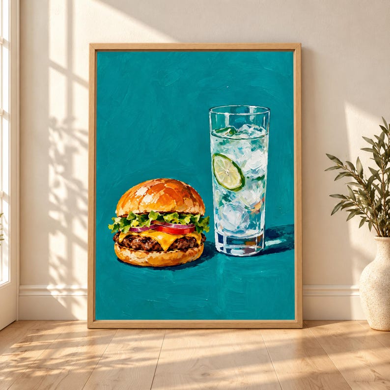 Framed cheeseburger wall art showing a loaded burger with melted cheese, lettuce, tomato and onion beside a tall iced lime drink against a rich teal background.