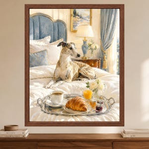 May include: A framed wall art print featuring a brindle greyhound resting on a white bedspread. A silver tray sits on the bed, holding a white coffee cup, a croissant, a glass of orange juice, and small jars of jam, with a blue headboard behind.