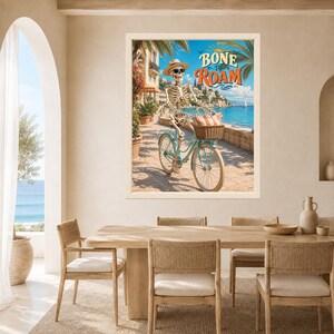 Peut inclure: Une impression d'art encadr&eacute;e repr&eacute;sentant un squelette portant un chapeau de paille et des lunettes de soleil, &agrave; v&eacute;lo sur un chemin c&ocirc;tier. Le texte BONE TO ROAM est &eacute;crit en lettres orange et bleues au-dessus d'une mer bleue et de palmiers.