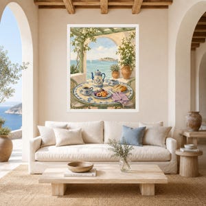 May include: A framed wall art print depicting a Mediterranean coastal scene with a round tiled table set for tea. The table features a blue and white teapot, matching cups, a plate of figs, and a pastry, all framed by a pergola overlooking the sea.