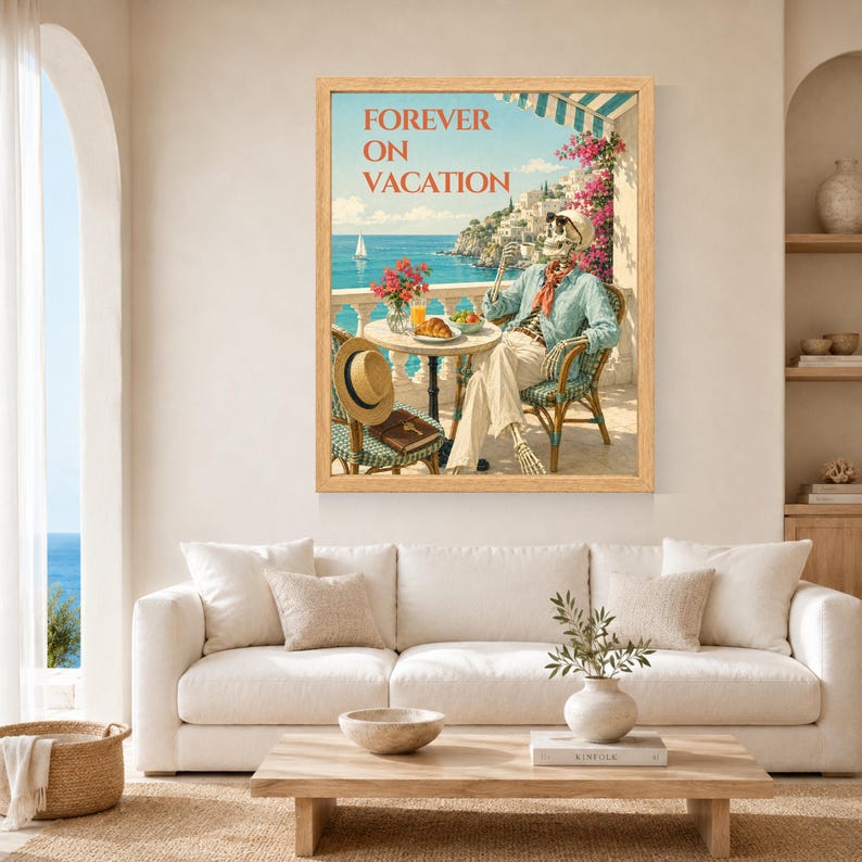 May include: A framed wall art print titled FOREVER ON VACATION featuring a skeleton sitting at a cafe table on a balcony overlooking the sea. The skeleton wears a light blue shirt and red scarf, with a straw hat on a chair and a croissant on the table.