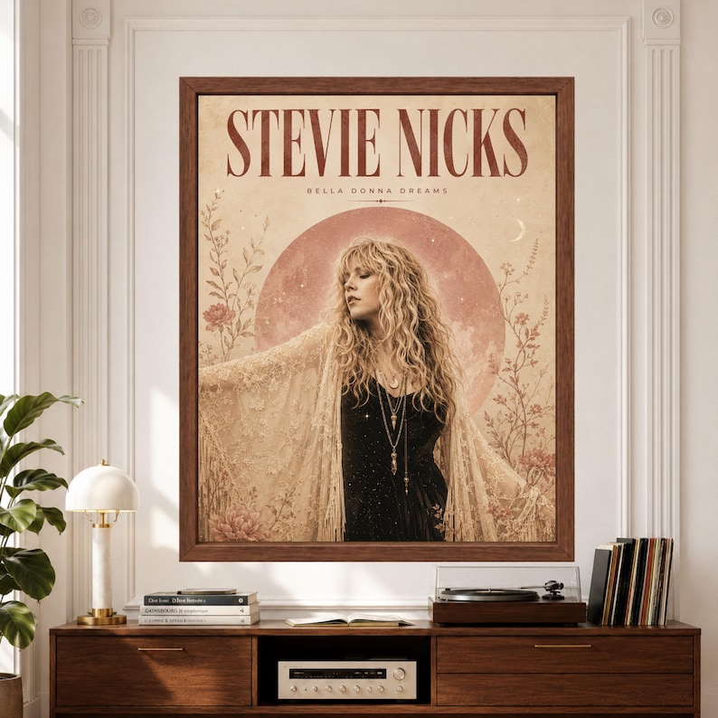 Framed Stevie Nicks wall art with a female rock singer in a black dress and cream lace shawl, surrounded by muted pink flowers, stars and a crescent moon on an aged beige background.