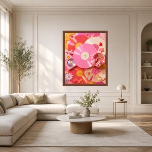 May include: A framed wall art print featuring a vibrant collage of vinyl records in shades of pink, red, and cream, accented with pink headphones, small star shapes, a white flower, and abstract liquid paint splashes in a bright, colourful composition.
