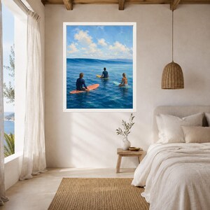 May include: A framed wall art print depicting three individuals on surfboards in the ocean. The scene shows a blue sea with a large wave, a clear sky with white clouds, and surfers on orange, yellow, and light blue boards facing the horizon.