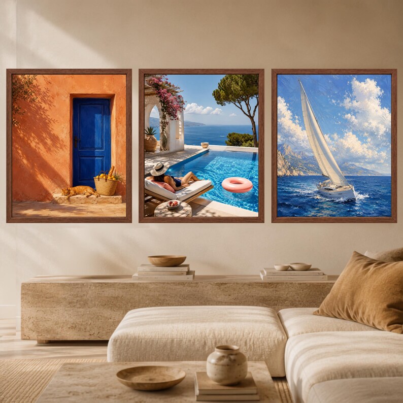 May include: A set of three framed wall art prints. The left print shows an orange wall with a blue door and a cat. The middle print depicts a swimming pool with a lounge chair and a pink float. The right print features a sailboat on the ocean.