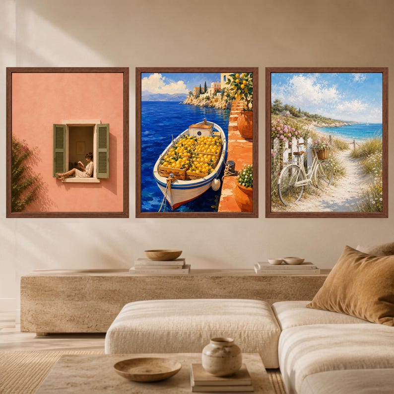 May include: A set of three framed wall art prints featuring Mediterranean scenes. The left print shows a person in a window on a peach wall. The center print depicts a boat filled with lemons on blue water. The right print shows a bicycle on a path.