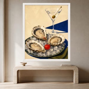 May include: A framed painting depicting three raw oysters on a bed of crushed ice in a dark bowl, accompanied by a bright red cherry and a martini glass containing a single green olive, set against a cream and deep blue geometric background.