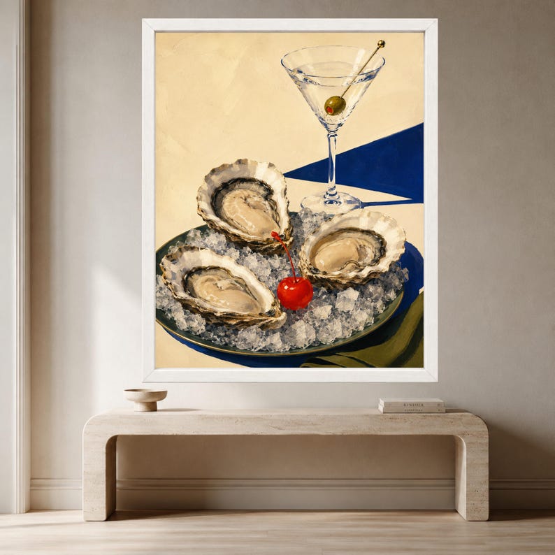 May include: A framed painting depicting three raw oysters on a bed of crushed ice in a dark bowl, accompanied by a bright red cherry and a martini glass containing a single green olive, set against a cream and deep blue geometric background.