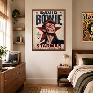 May include: A framed wall poster featuring a portrait of David Bowie with his iconic lightning bolt makeup. The text reads DAVID BOWIE, STARMAN, THERE'S A STARMAN WAITING IN THE SKY, and HE'D LIKE TO COME AND MEET US, set against a large red star.