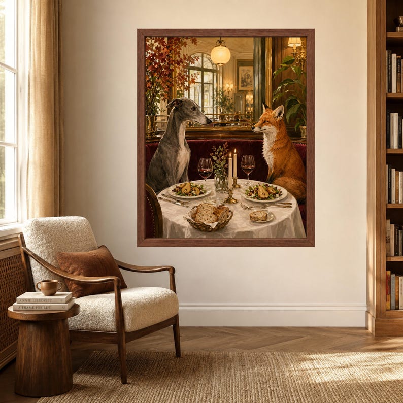 May include: A framed wall art print depicting a grey whippet and an orange fox sitting opposite each other at a round dining table. The table is set with plates of food, wine glasses, and lit candles, all within a dark wood frame on a wall.