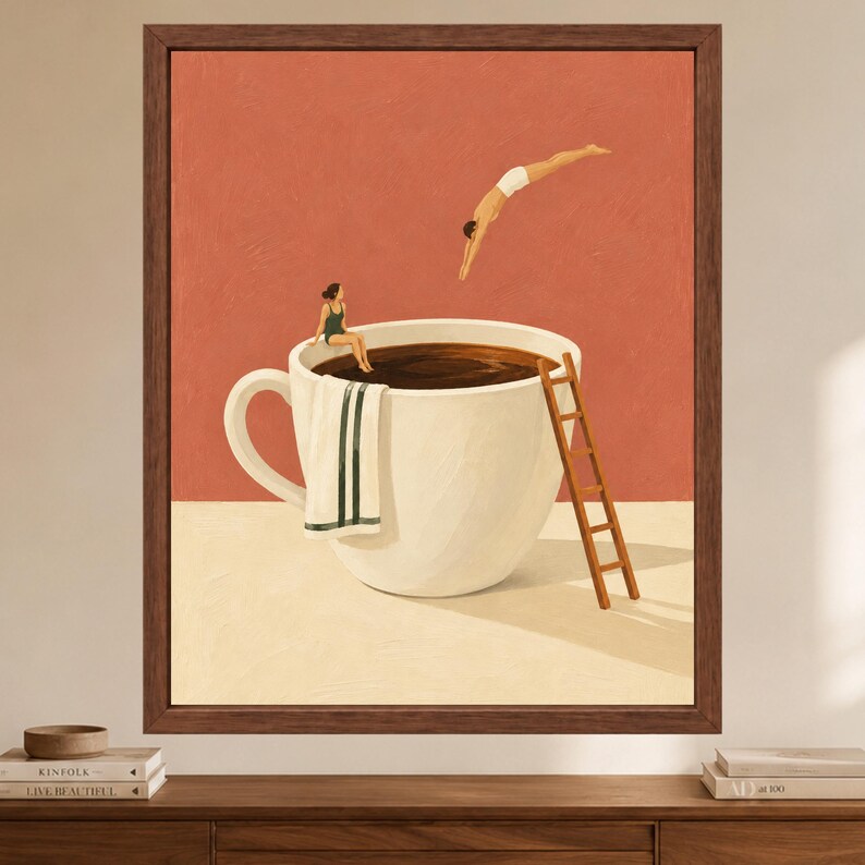 May include: A framed wall art print featuring a large white coffee cup filled with dark liquid against a terracotta background. A person in a green swimsuit sits on the rim with a towel, while another person dives into the coffee from above.