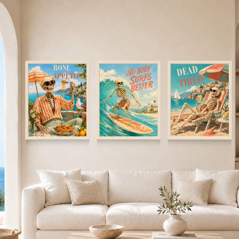 May include: Three framed wall art prints featuring skeletons in beach settings. The left print shows a skeleton eating pasta with the text BONE APPETIT. The center print shows a skeleton surfing with the text NO BODY SURFS BETTER. The right print shows a skeleton relaxing under an umbrella with the text DEAD TIRED.