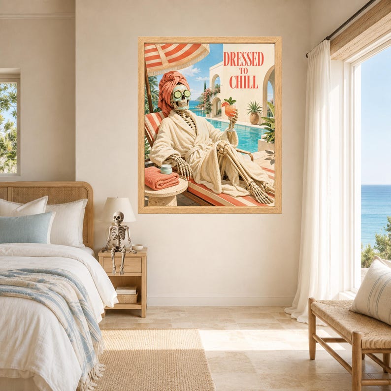 May include: A framed wall art print featuring a skeleton wearing a beige bathrobe, a pink towel wrap, and cucumber slices over its eyes. The skeleton sits on a lounge chair by a pool, holding a cocktail, with the text DRESSED TO CHILL above.