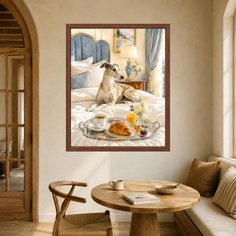 May include: A framed wall art print depicting a brindle whippet resting on a white bed with a blue headboard. A silver tray on the bed holds a cup of coffee, a croissant, a glass of orange juice, and a small jar of jam near a bedside lamp.