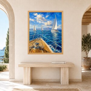 May include: A framed wall art print depicting a view from the wooden deck of a sailboat looking out over a deep blue sea. Three white sailboats with sails raised are visible on the horizon under a bright blue sky with scattered white clouds.
