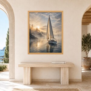 May include: A framed wall art print featuring a sailboat gliding across calm water during a misty sunrise. The scene includes a dense forest shoreline partially obscured by fog, with soft golden light reflecting on the water surface.