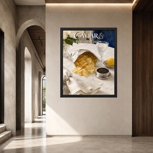 May include: A framed wall art print titled Caviar & Potato Chips featuring a silver bag of golden potato chips, a small metal tin of black caviar, a crystal glass, a lemon, and a white napkin with a shell napkin ring on a white tablecloth.