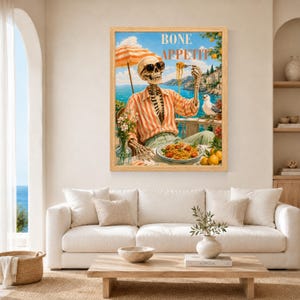 Peut inclure: Une impression d'art encadr&eacute;e repr&eacute;sentant un squelette portant des lunettes de soleil et une chemise ray&eacute;e orange, assis &agrave; une table avec une assiette de p&acirc;tes. Le texte BONE APPETIT est inscrit en haut. Une mouette est sur une balustrade.