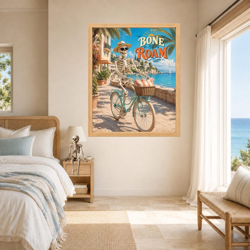 Peut inclure: Une impression d'art encadr&eacute;e repr&eacute;sentant un squelette portant un chapeau de paille et des lunettes de soleil, chevauchant un v&eacute;lo bleu clair avec un panier en osier sur un chemin c&ocirc;tier. Le texte BONE TO ROAM est &eacute;crit en orange et blanc.