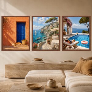 Pu&ograve; includere: Un set di tre stampe artistiche da parete incorniciate con scene mediterranee. La stampa a sinistra mostra una parete arancione con una porta blu e un gatto. Quella centrale raffigura una scogliera costiera con tavoli. Quella a destra mostra una piscina con una persona.