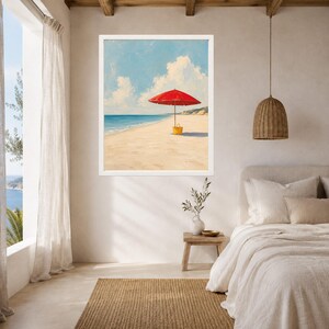 May include: A framed wall art print depicting a bright red beach umbrella standing on a sandy shore next to a yellow tote bag. The scene features a calm blue ocean under a light blue sky with white clouds, capturing a peaceful coastal landscape.