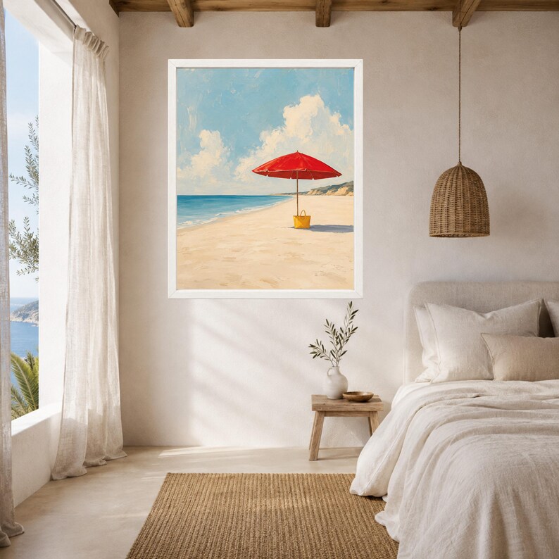 May include: A framed wall art print depicting a bright red beach umbrella standing on a sandy shore next to a yellow tote bag. The scene features a calm blue ocean under a light blue sky with white clouds, capturing a peaceful coastal landscape.