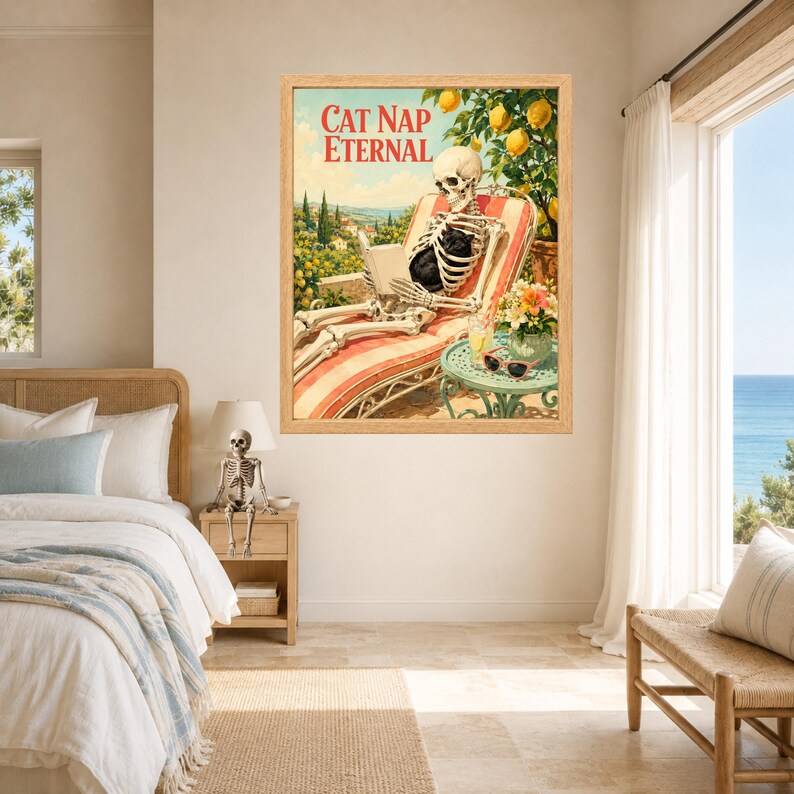 May include: A framed wall art print titled CAT NAP ETERNAL featuring a skeleton lounging on a striped deck chair, reading a book under a lemon tree. A small table holds a drink and sunglasses, with a black cat resting on the skeleton's lap.