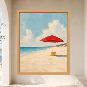 May include: A framed painting depicting a sandy beach scene under a blue sky with white clouds. A bright red beach umbrella stands on the sand, casting a shadow, with a yellow tote bag placed at the base of the umbrella pole near the ocean.