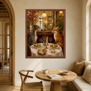 May include: A framed wall art print depicting a grey whippet and an orange fox sitting at a round table set for dinner. The table features a white tablecloth, two plates with food, two wine glasses, two lit candles, and a basket of bread.