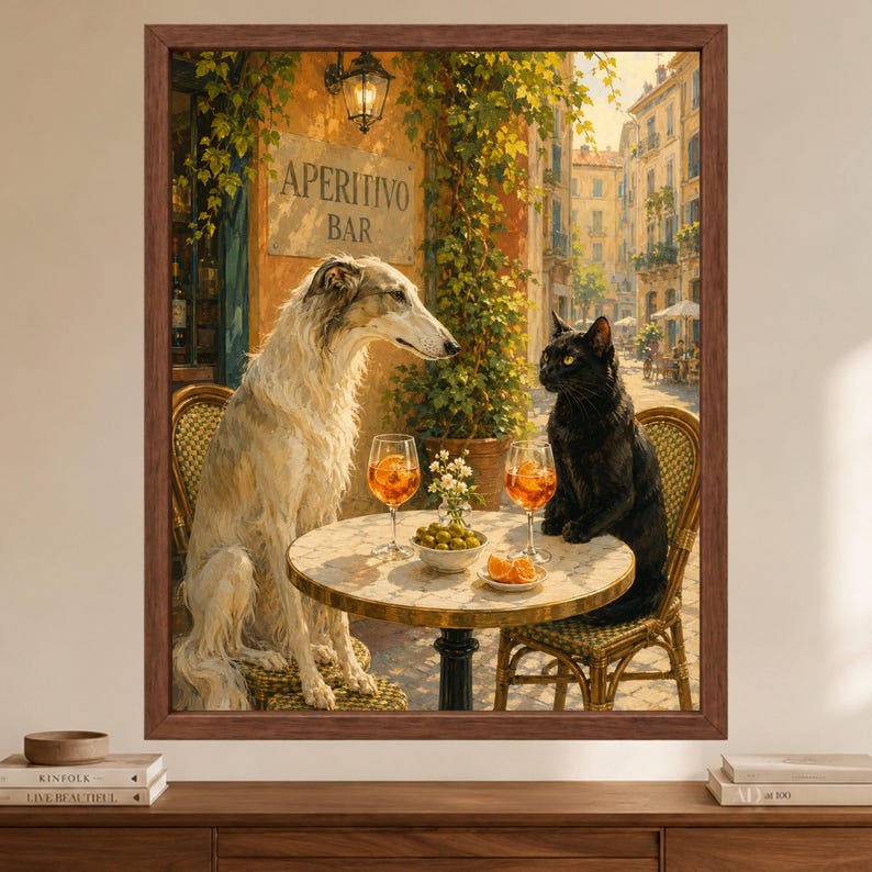 May include: A framed wall art print depicting a long-haired white Borzoi dog and a black cat sitting on chairs at a small round table. The table holds two glasses of orange liquid, a bowl of green olives, and orange slices. A sign reads APERITIVO BAR.