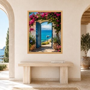 May include: A framed wall art print depicting an open blue wooden door set in a white stone wall, framed by vibrant pink bougainvillea flowers. The view through the doorway reveals a bright blue sea with a small white boat under a clear sky.