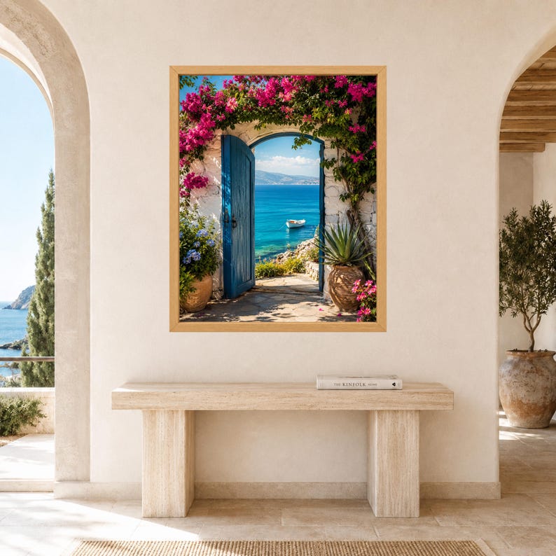 May include: A framed wall art print depicting an open blue wooden door set in a white stone wall, framed by vibrant pink bougainvillea flowers. The view through the doorway reveals a bright blue sea with a small white boat under a clear sky.