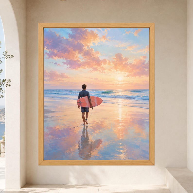 May include: A framed wall art print featuring a person walking on a wet sandy beach at sunset while carrying a coral-colored surfboard. The sky is filled with soft pink and orange clouds reflecting on the water and the wet sand below.