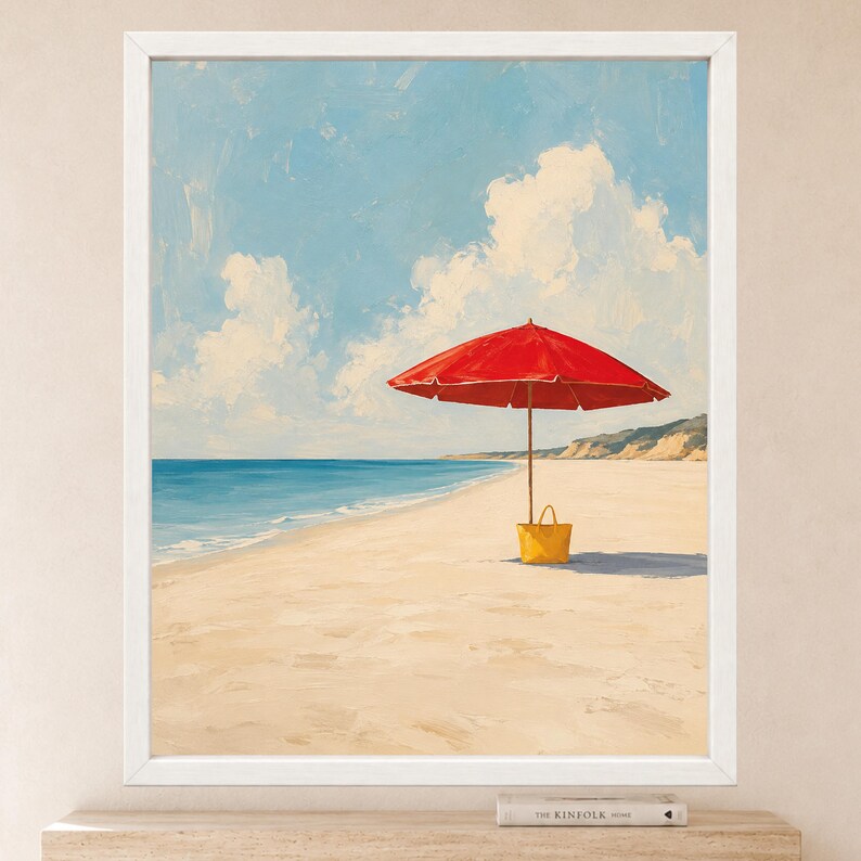 May include: A framed painting depicting a bright red beach umbrella and a yellow tote bag on a sandy beach. The scene features a calm blue ocean, a clear sky with white clouds, and a distant coastline, all rendered in a painterly style.
