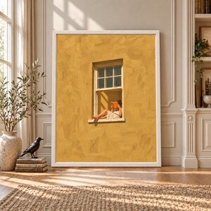Framed mustard yellow wall art showing a barefoot woman sitting in an open cream window while reading an orange book against a textured warm yellow wall.