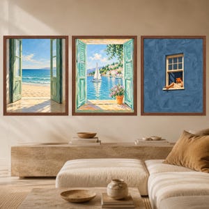 May include: A set of three framed wall art prints. The left print shows an open window overlooking a sandy beach and ocean. The middle print depicts a sailboat on blue water seen through an open window. The right print shows a person reading in a window.