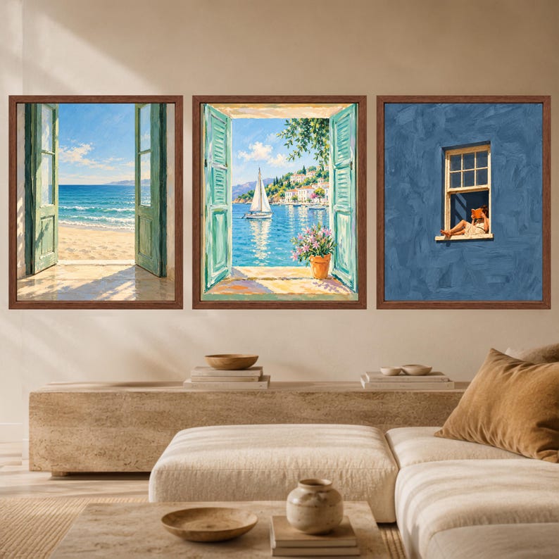 May include: A set of three framed wall art prints. The left print shows an open window overlooking a sandy beach and ocean. The middle print depicts a sailboat on blue water seen through an open window. The right print shows a person reading in a window.