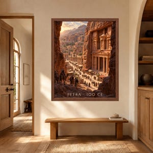 May include: A framed wall art print depicting the ancient city of Petra with its carved sandstone architecture, columns, and figures with camels on a path. The image features warm golden lighting and includes the text PETRA 100 CE at the bottom.