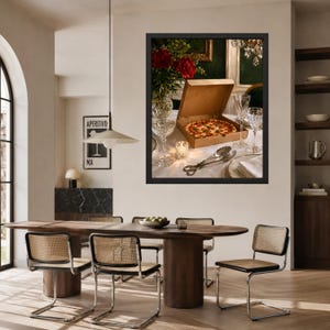 May include: A framed wall art print depicting a dining table scene with a cardboard pizza box containing a whole pizza, a crystal vase with red flowers, two crystal wine glasses, a small lit candle, and silver serving tongs on a white cloth.