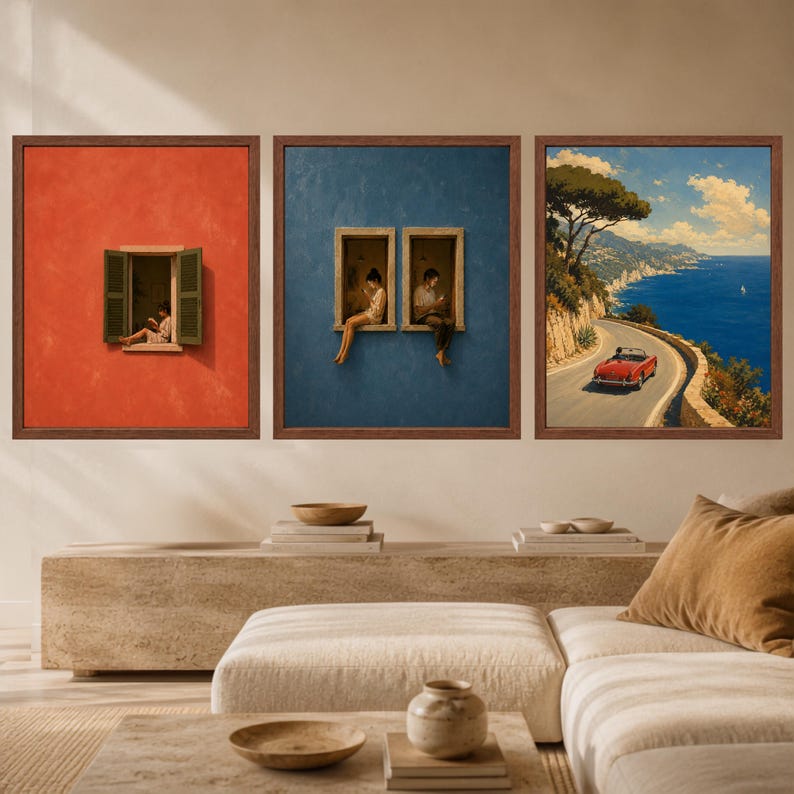 Op de afbeelding: Een set van drie ingelijste wandkunstwerken. De linker print toont een persoon die leest in een raam op een rode muur. De middelste print toont twee personen in aparte ramen op een blauwe muur. De rechter print toont een rode auto op een kustweg.
