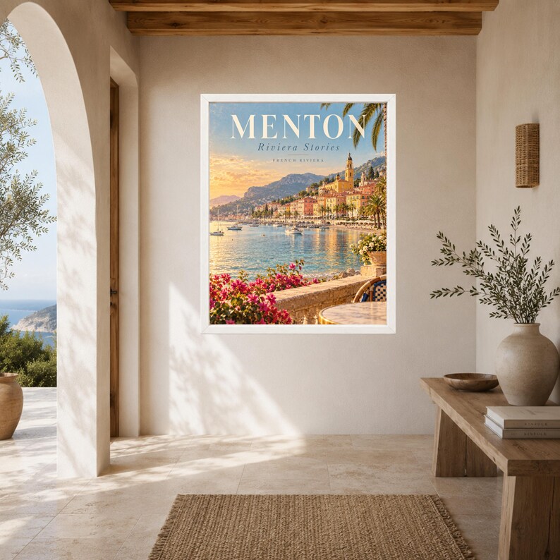 May include: A framed wall art print featuring a scenic view of Menton on the French Riviera. The image displays a coastal town with colorful buildings, a calm sea with boats, and bright pink flowers in the foreground under a warm sunset sky.