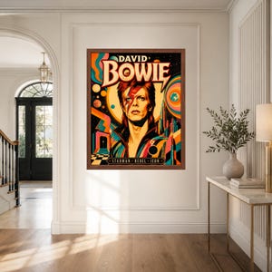 May include: A rectangular framed wall art print featuring a stylized portrait of David Bowie with a red lightning bolt across the face. The vibrant background includes colorful concentric circles, planets, and a city skyline with the text DAVID BOWIE.