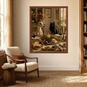 Op de afbeelding: Een ingelijste kunstdruk met een grijs-witte whippet en een zwarte kat aan een eettafel vol met een pompoen, druiven, vijgen, brood, olijven en wijnglazen. De sc&egrave;ne speelt zich af in een rustieke keuken met een houten buffetkast.