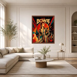 May include: A framed wall art print featuring a stylised illustration of David Bowie in a striped jumpsuit. The artwork includes a rocket, planets, and a red star against a dark background with bold geometric shapes in red, teal, and yellow.
